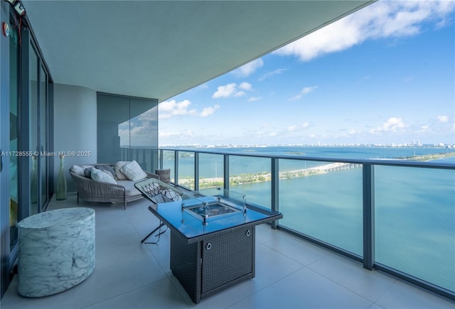 balcony with a water view and an outdoor living space with a fire pit