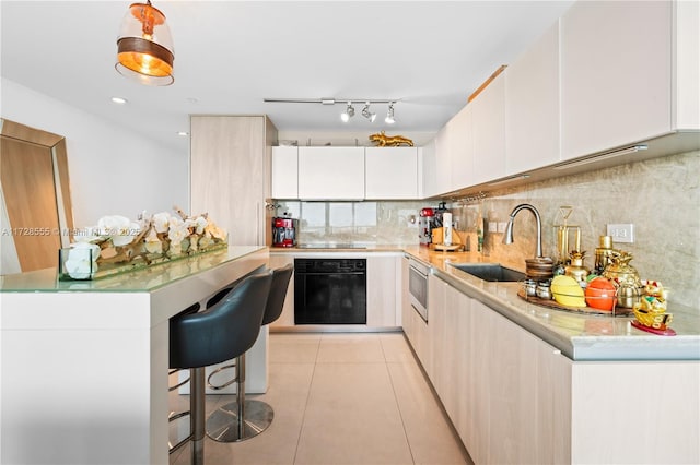 kitchen featuring sink, white cabinetry, stainless steel microwave, light tile patterned flooring, and oven