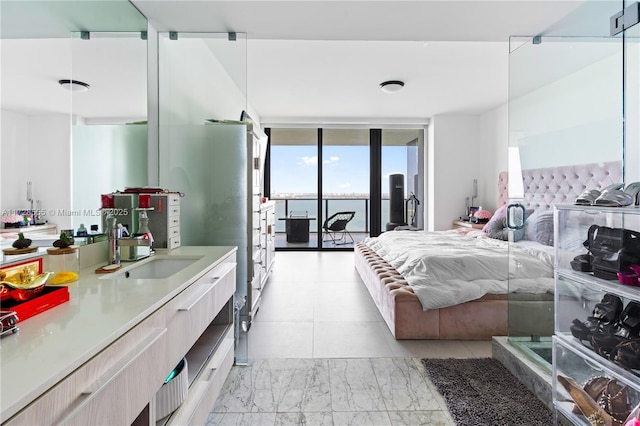 bedroom featuring sink, a wall of windows, and access to outside