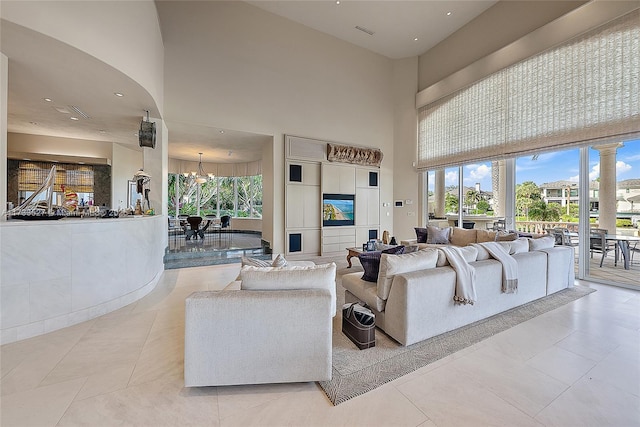 tiled living room featuring a chandelier and a high ceiling