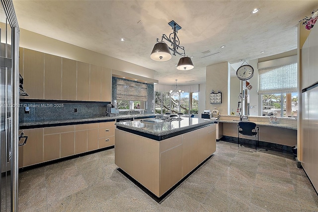 kitchen with stainless steel gas stovetop, backsplash, hanging light fixtures, a center island, and an inviting chandelier