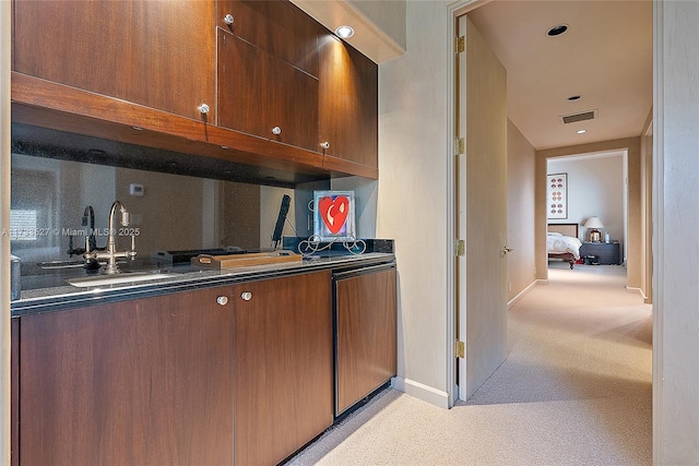 kitchen featuring tasteful backsplash, light colored carpet, and sink