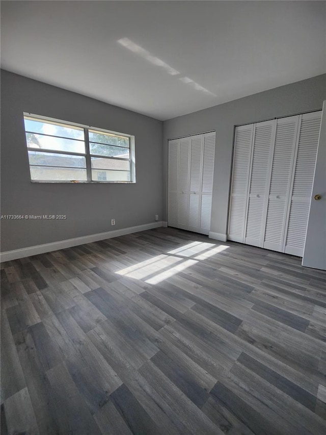 unfurnished bedroom with multiple closets and dark hardwood / wood-style flooring