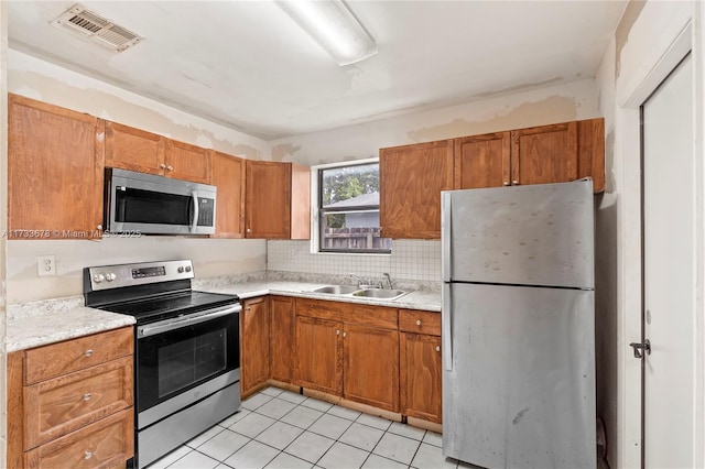 kitchen featuring tasteful backsplash, appliances with stainless steel finishes, sink, and light tile patterned floors