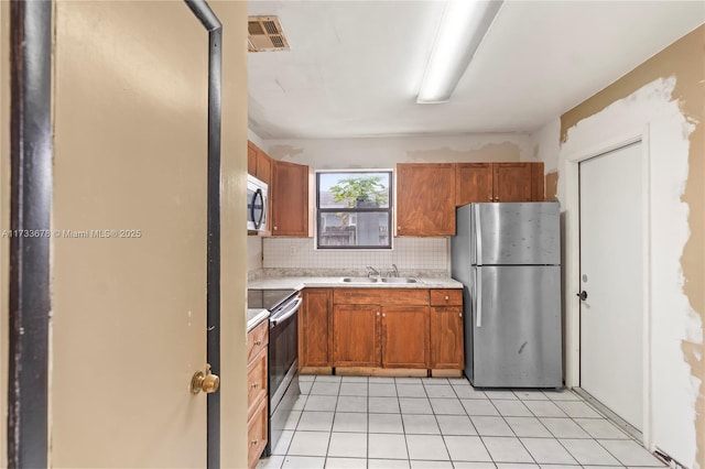 kitchen with sink, decorative backsplash, stainless steel appliances, and light tile patterned floors