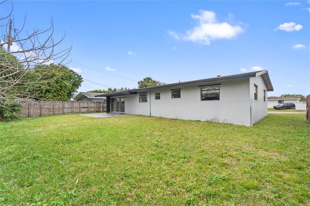 rear view of property featuring a lawn and a patio area