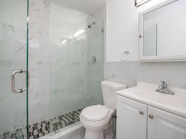 bathroom featuring tile walls, backsplash, vanity, toilet, and a shower with door