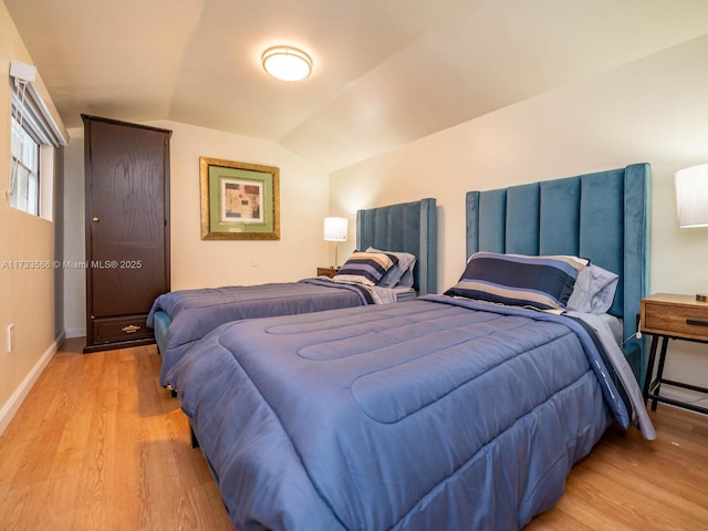 bedroom with vaulted ceiling and light hardwood / wood-style flooring