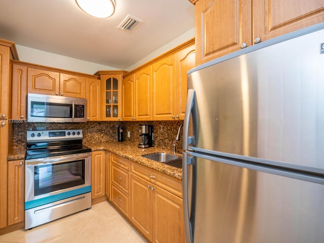 kitchen featuring light tile patterned flooring, sink, appliances with stainless steel finishes, stone counters, and decorative backsplash