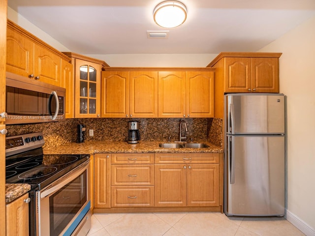 kitchen featuring light tile patterned flooring, stone countertops, tasteful backsplash, sink, and stainless steel appliances