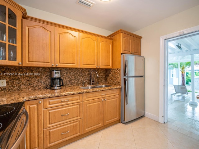 kitchen featuring sink, light tile patterned floors, dark stone countertops, backsplash, and stainless steel appliances