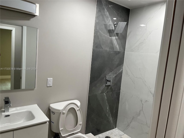 bathroom featuring vanity, tiled shower, and toilet