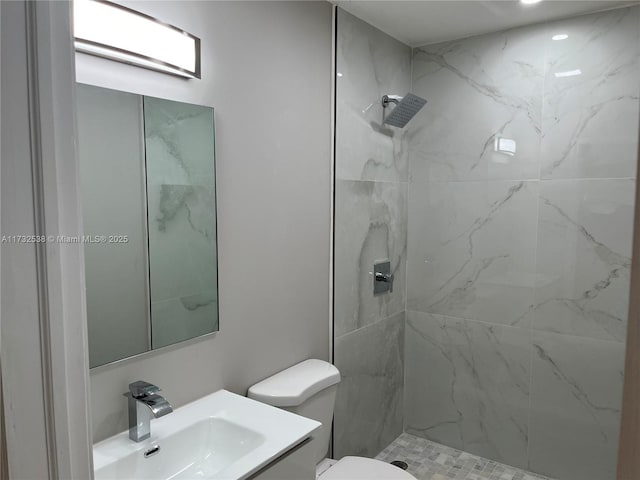 bathroom featuring a tile shower, vanity, and toilet