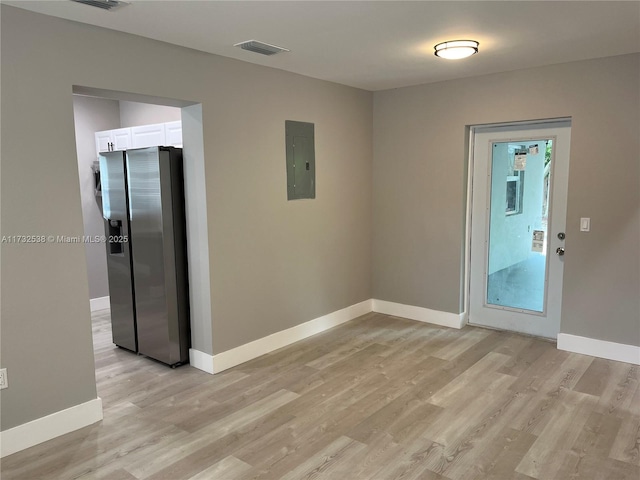 spare room featuring electric panel and light wood-type flooring