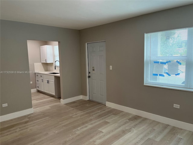 unfurnished room with sink and light hardwood / wood-style floors