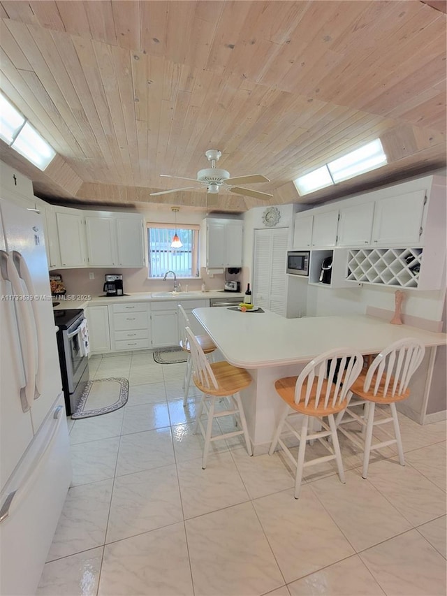 kitchen with sink, wood ceiling, appliances with stainless steel finishes, white cabinetry, and a kitchen bar