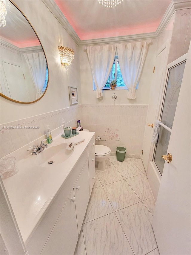 full bathroom with tile walls, enclosed tub / shower combo, vanity, toilet, and crown molding