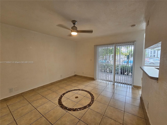 empty room featuring light tile patterned flooring, ceiling fan, and a textured ceiling