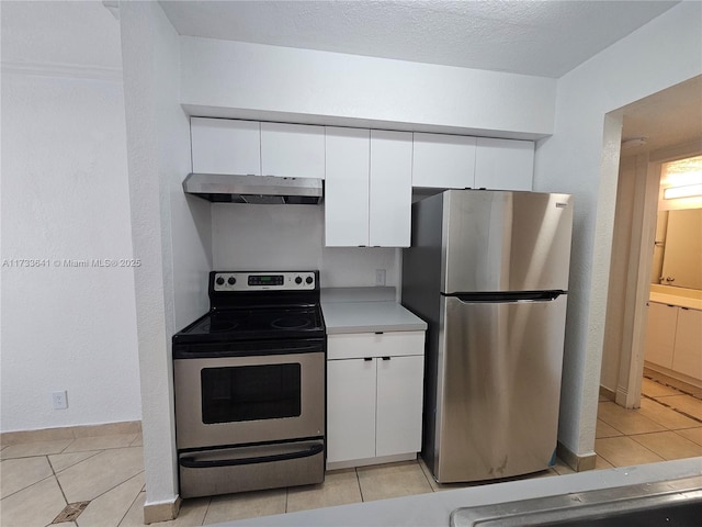 kitchen with stainless steel appliances, white cabinetry, light tile patterned floors, and a textured ceiling