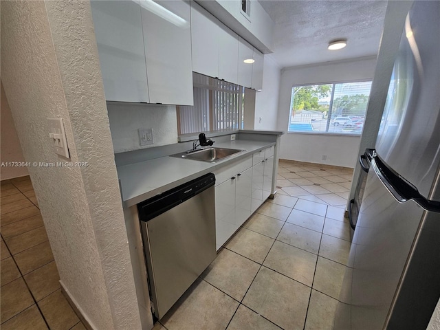 kitchen with sink, white cabinetry, a textured ceiling, light tile patterned floors, and appliances with stainless steel finishes