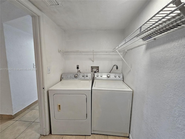 washroom with washing machine and clothes dryer and light tile patterned floors