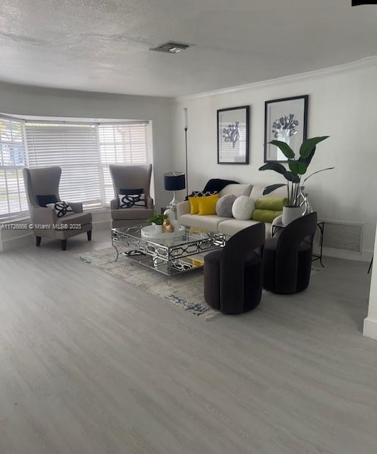 living room with crown molding, a healthy amount of sunlight, and hardwood / wood-style floors