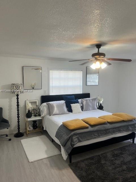 bedroom with hardwood / wood-style flooring, ceiling fan, crown molding, and a textured ceiling