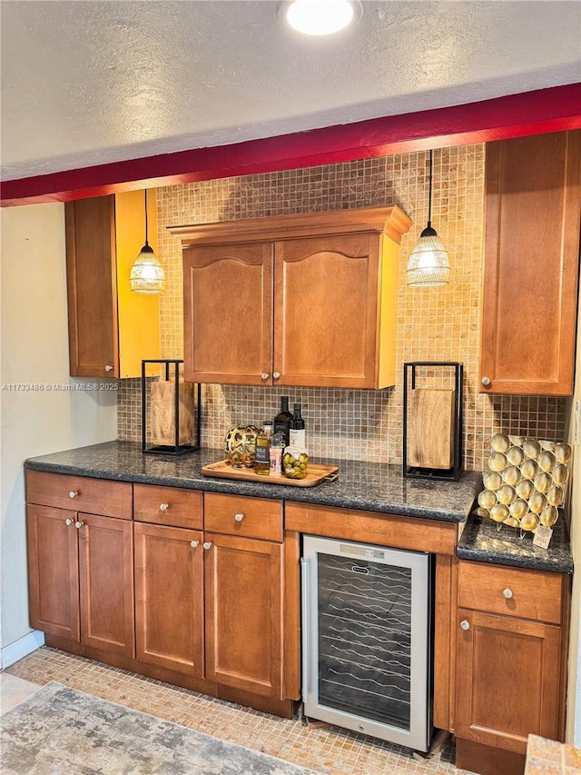 kitchen with wine cooler, pendant lighting, a textured ceiling, tasteful backsplash, and brown cabinets