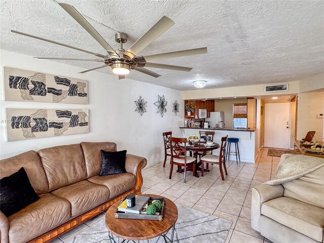 tiled living room with ceiling fan and a textured ceiling