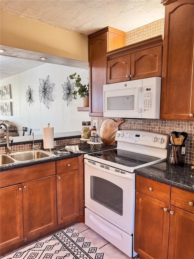 kitchen featuring sink, decorative backsplash, light tile patterned floors, white appliances, and a textured ceiling