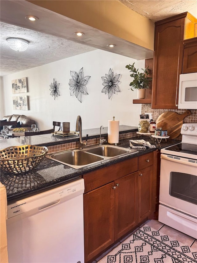 kitchen featuring light tile patterned floors, decorative backsplash, white appliances, a textured ceiling, and a sink