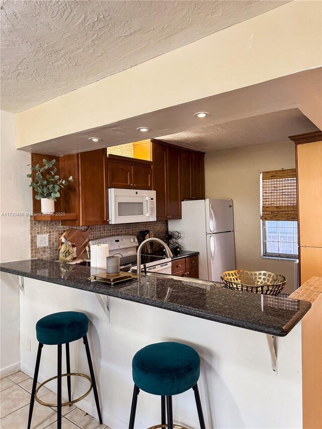 kitchen featuring backsplash, white appliances, sink, and a textured ceiling