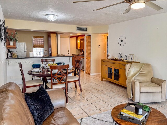 living room with ceiling fan, a textured ceiling, and light tile patterned floors