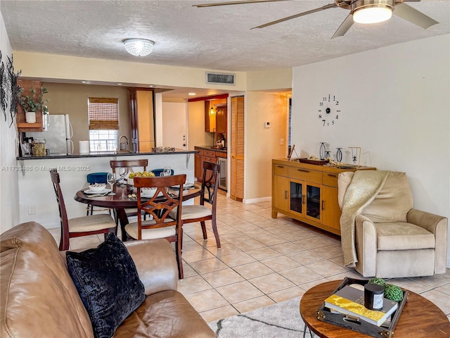 dining room featuring light tile patterned floors, visible vents, ceiling fan, wine cooler, and a textured ceiling