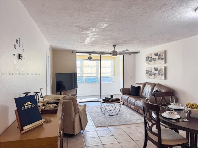 living area featuring a textured ceiling, light tile patterned flooring, and ceiling fan