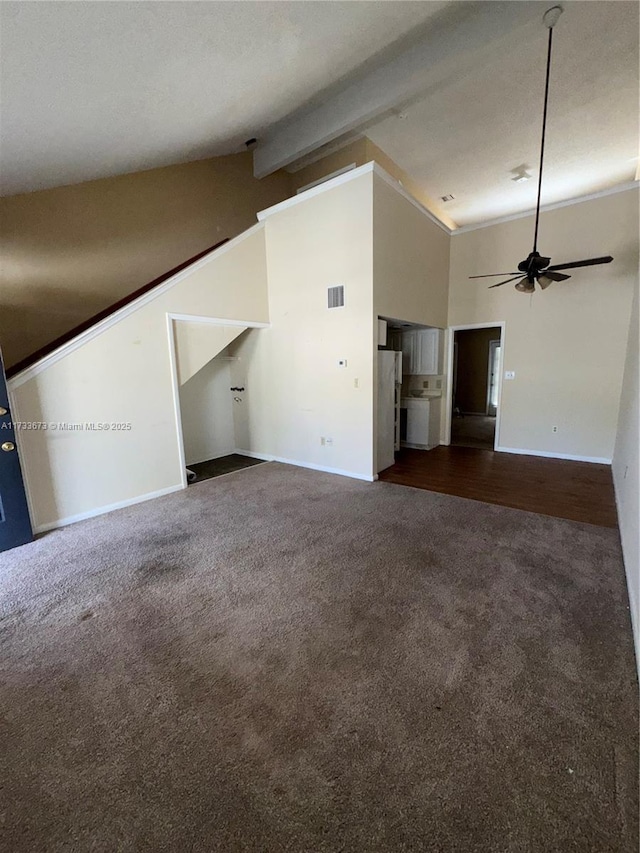 unfurnished living room with beamed ceiling, ceiling fan, high vaulted ceiling, and dark colored carpet