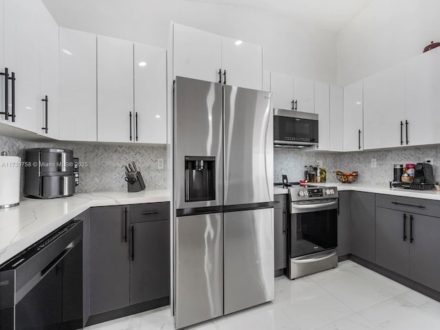 kitchen with white cabinetry, appliances with stainless steel finishes, light stone counters, and decorative backsplash