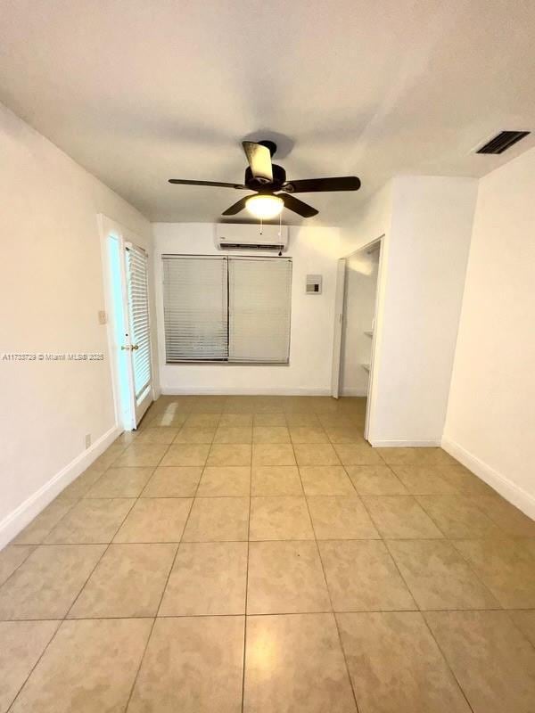 empty room featuring light tile patterned floors, a wall mounted AC, and ceiling fan