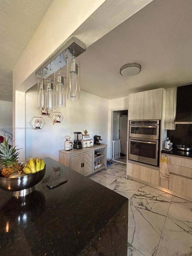 kitchen featuring decorative light fixtures, double oven, and light brown cabinets