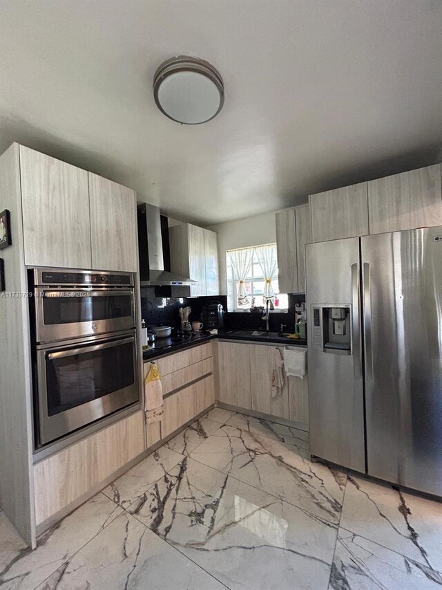 kitchen with wall chimney range hood, light brown cabinets, sink, and appliances with stainless steel finishes