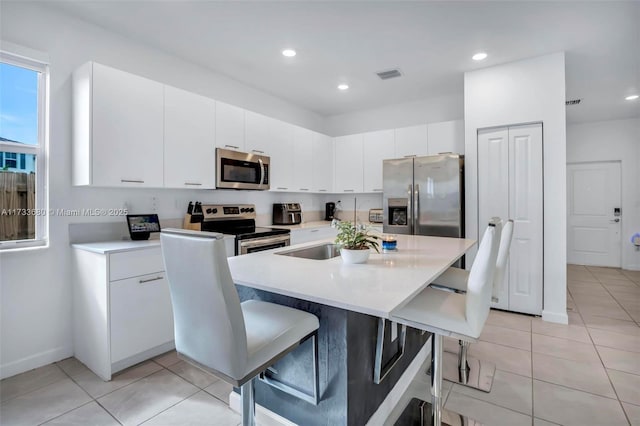 kitchen featuring sink, a breakfast bar area, white cabinets, and appliances with stainless steel finishes