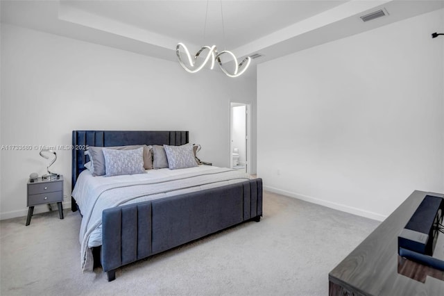 bedroom with a tray ceiling, a chandelier, and carpet