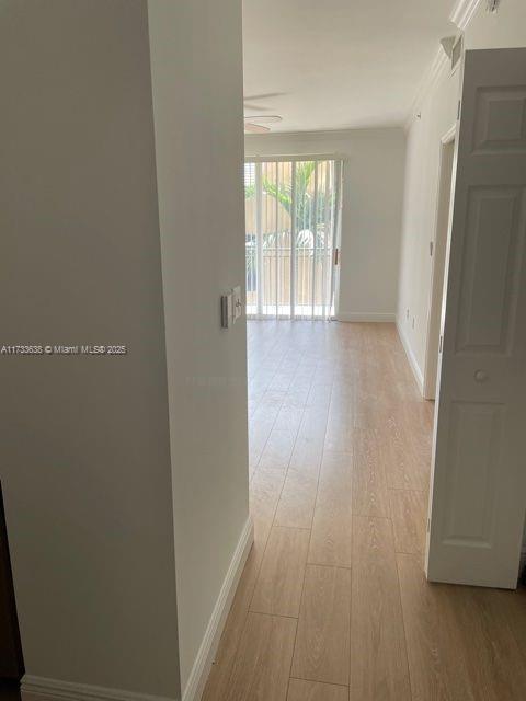 corridor with ornamental molding and light wood-type flooring