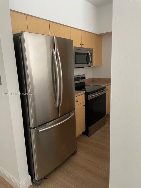 kitchen featuring appliances with stainless steel finishes, light brown cabinets, and light hardwood / wood-style floors