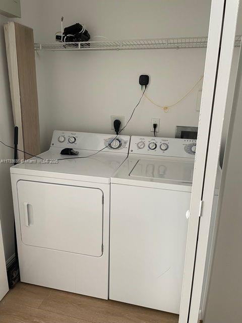 clothes washing area with wood-type flooring and washing machine and dryer