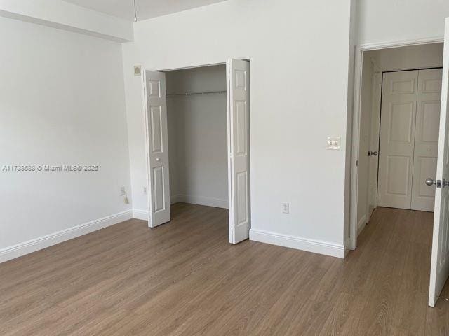 unfurnished bedroom featuring wood-type flooring and a closet