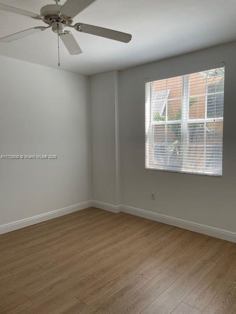 spare room with ceiling fan and light wood-type flooring