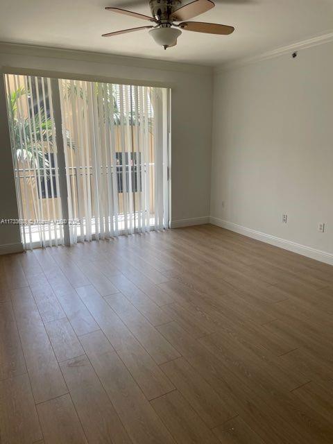 spare room featuring wood-type flooring, plenty of natural light, crown molding, and ceiling fan