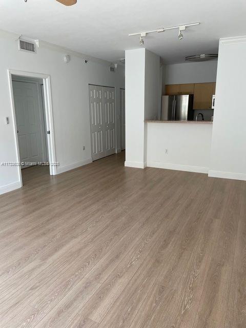 unfurnished living room featuring light hardwood / wood-style flooring and track lighting