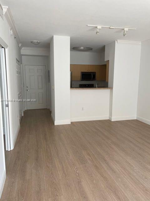 unfurnished living room with ornamental molding and light wood-type flooring